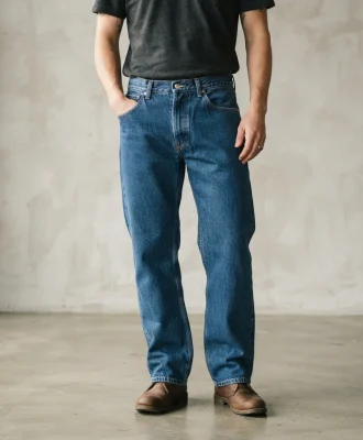 Mode Of One men's rigid waist loose fit jean in blue, shown on a model from the waist down to illustrate the relaxed, comfortable fit.